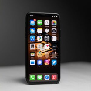 Close-up of a smartphone with an array of app icons against dark background.